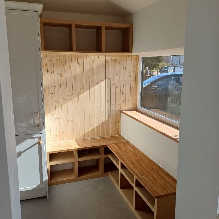 Boot room with built-in timber seating and storage inside the converted garage